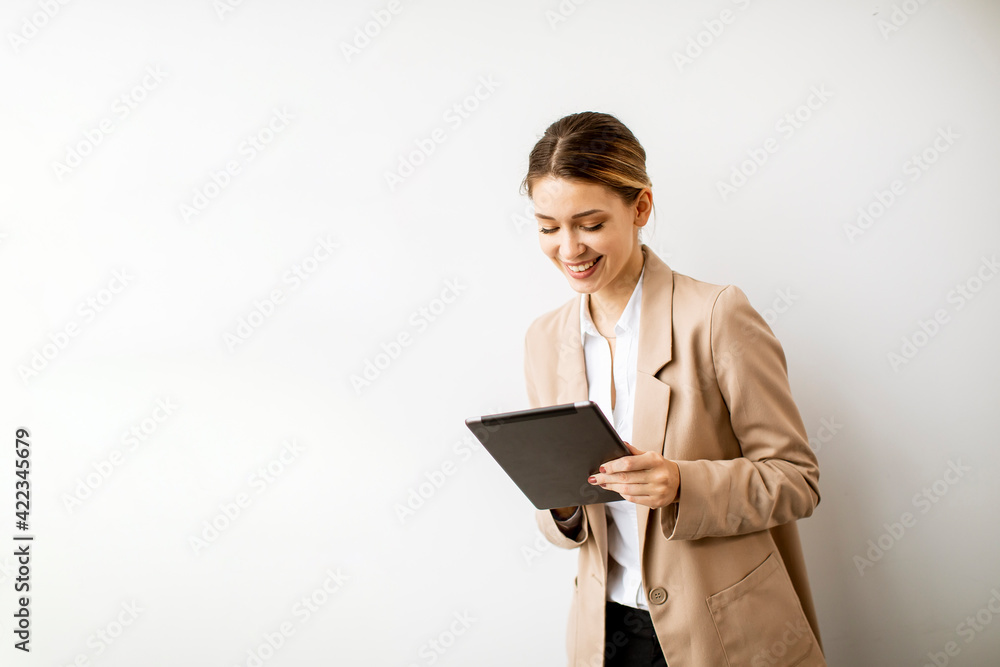 Young woman holding digital tablet by the white wall in modern office Young woman holding digital tablet by the white wall in modern office
