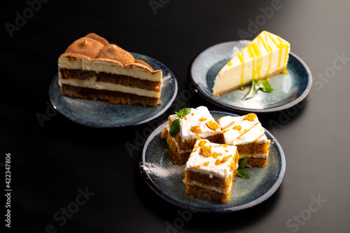 Photography A few different desserts, assorted sweets on plates on a black background