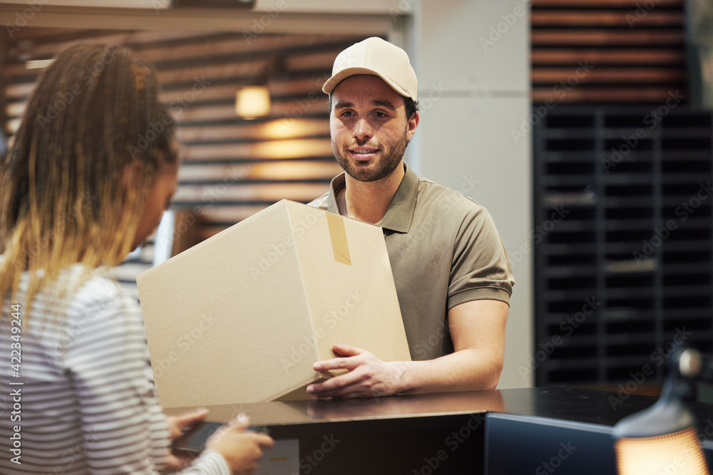 Smiling courier delivering a package in an office Smiling courier delivering a package in an office