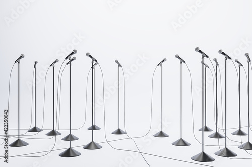 Business speaking performance concept with lots of floor stand microphones on light floor at white wall background