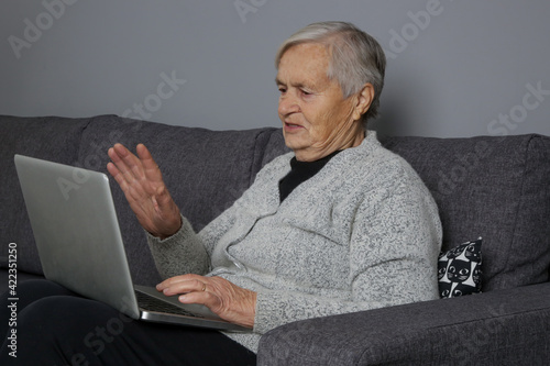 Senior Caucasian woman sitting on sofa and using laptop