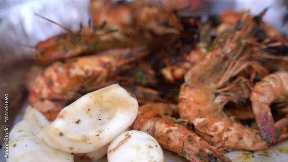 Putting ready to eat grilled seafood into aluminium foil plate Putting ready to eat grilled seafood into aluminium foil plate