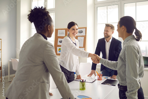 Business handshake. Happy young people greeting each other in group meeting. Smiling manager shaking hands with client after successful negotiation at the company office