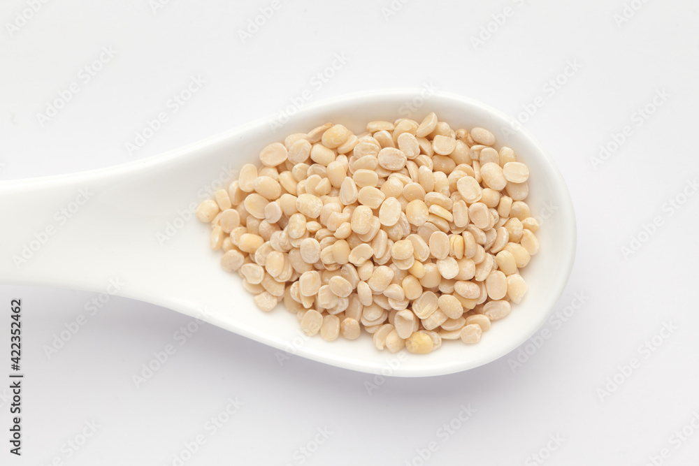 macro Close-up of Organic split polished white urad dal (Vigna mungo) on a white ceramic soup spoon. Top view macro Close-up of Organic split polished white urad dal (Vigna mungo) on a white ceramic soup spoon. Top view