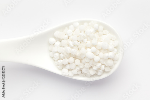 Macro Close up of organic white sago or sabudana big size on a white ceramic soup spoon. Top view