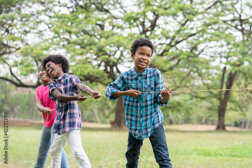 Happy African American childrens playing rope tug of war in the park, Education outdoor concept