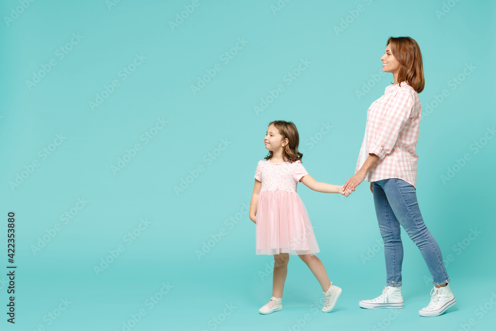 Full length woman in pink clothes have fun with child baby girl 5-6 years old. Mommy little kid daughter walk go step isolated on pastel blue azure background studio. Mother's Day love family concept. Full length woman in pink clothes have fun with child baby girl 5-6 years old. Mommy little kid daughter walk go step isolated on pastel blue azure background studio. Mother's Day love family concept.