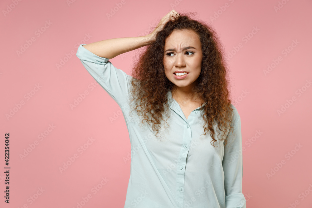 Young black african american puzzled thoughtful pensive mistaken stressed curly woman 20s wearing casual blue shirt looking aside holding head isolated on pastel pink color background studio portrait. Young black african american puzzled thoughtful pensive mistaken stressed curly woman 20s wearing casual blue shirt looking aside holding head isolated on pastel pink color background studio portrait.