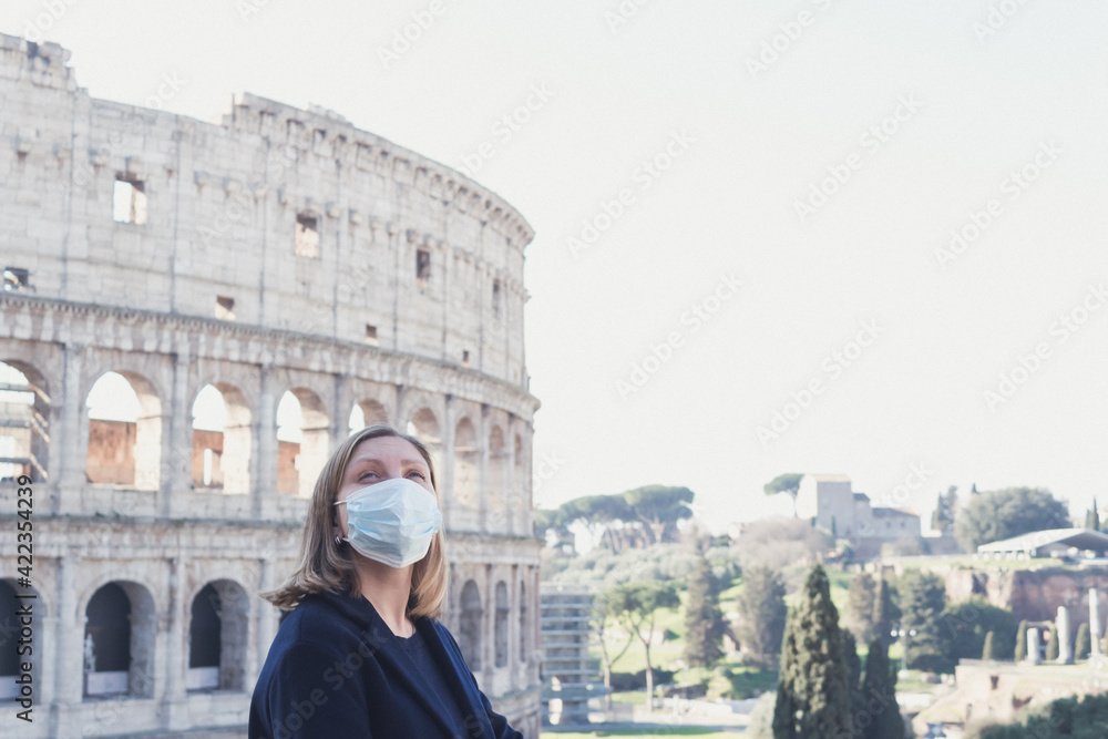 young woman in the medical protective mask near Coliseum. COVID-19 pandemic in Italy