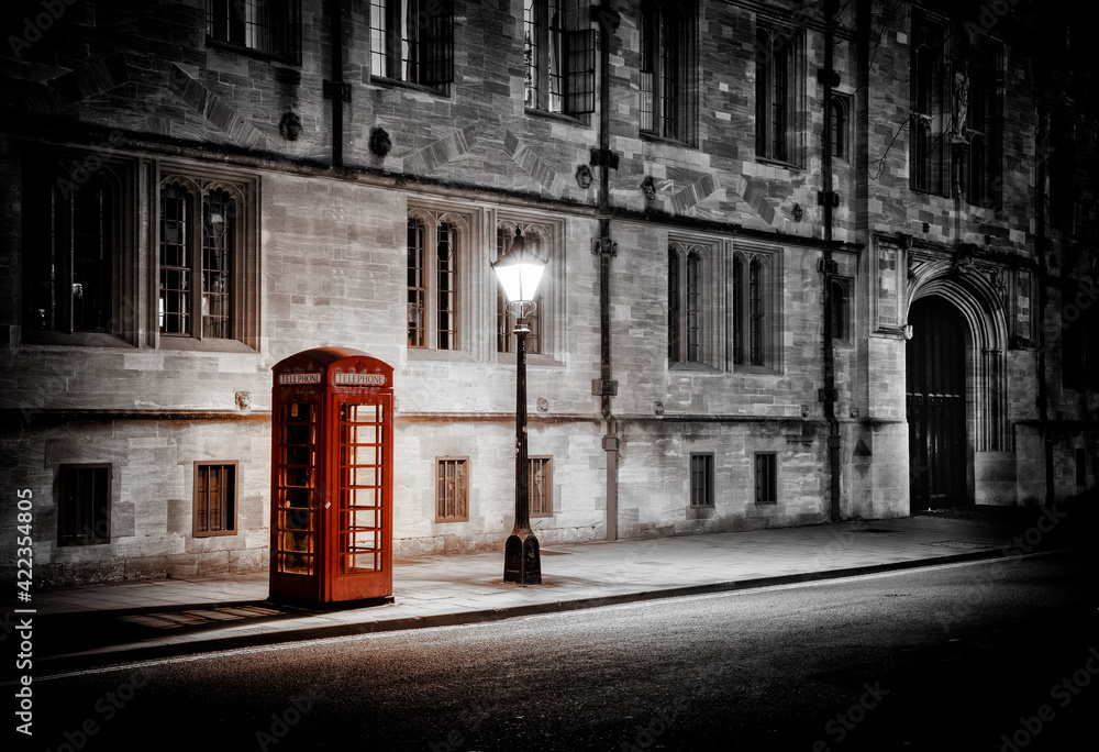 Fototapeta premium Illuminated Iconic Red British Telephone Box In Oxford City Centre After Dark During Lockdown