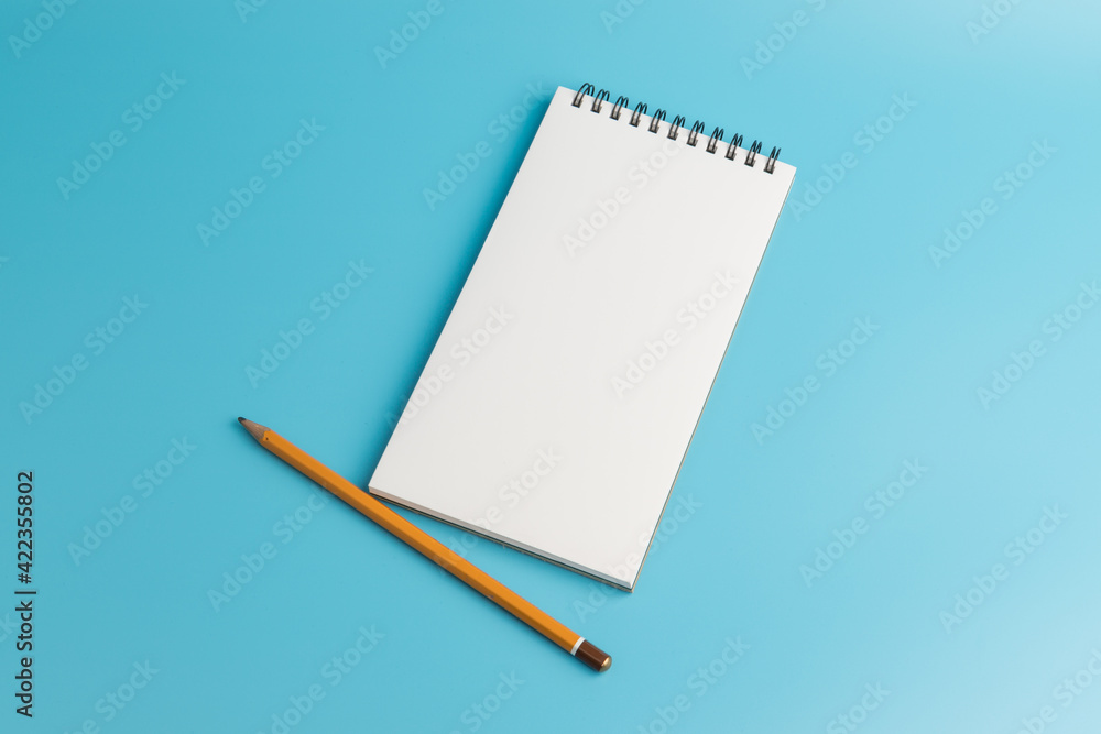 White notebook,pencil, on blue background. top view copy space White notebook,pencil, on blue background. top view copy space