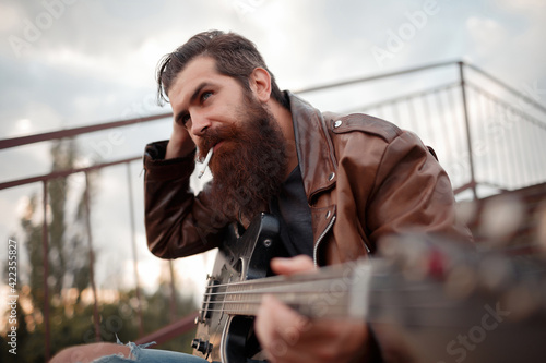 Fotografie a man with a long red beard and gray hair in a brown leather jacket holds an ele