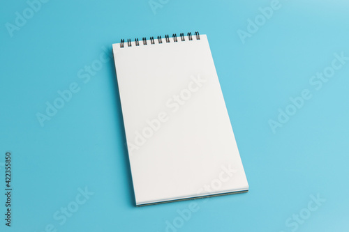 White notebook  on blue background. top view, copy space