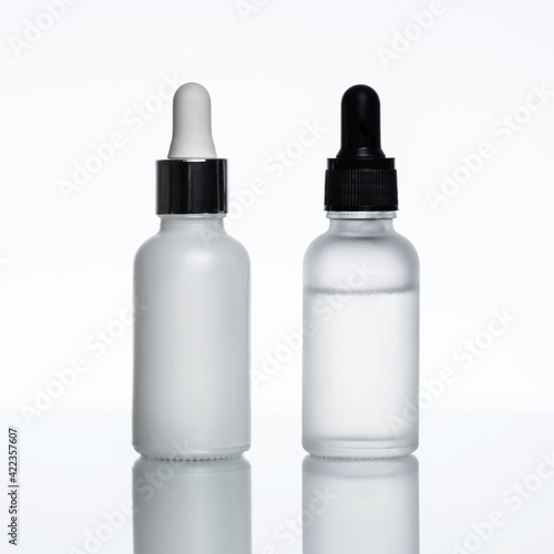 Bottles of serum on a light background. Moisturizer, vitamin C, hyaluronic acid.