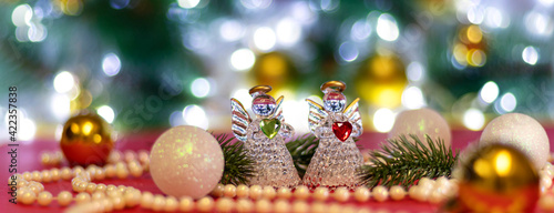 Banner with Two angels with blur white Christmas balls and Christmas beads on bokeh background. Christmas background or Christmas card. New Year or Xmas concept. Copy space.