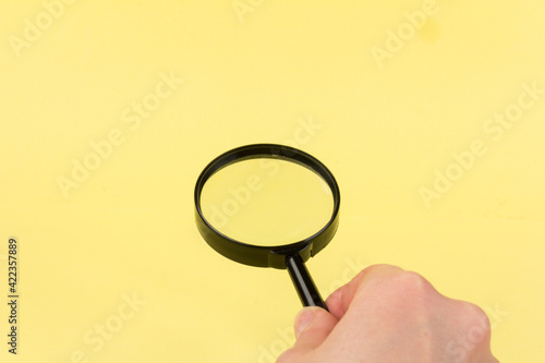 magnifying glass, loupe in hand, search symbol on yellow background with copy space