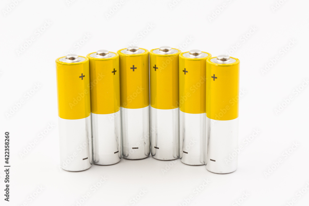 Photo of gray-yellow alkaline AA batteries on white background. Recycling of rechargeable NiMH batteries. The most popular size of accumulators. Copy space. Photo of gray-yellow alkaline AA batteries on white background. Recycling of rechargeable NiMH batteries. The most popular size of accumulators. Copy space.