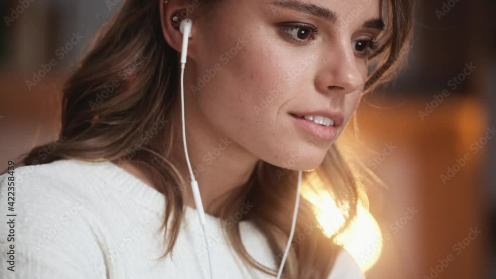 A close-up view of a beautiful businesswoman with wired earphones is working with her laptop while sitting in the office A close-up view of a beautiful businesswoman with wired earphones is working with her laptop while sitting in the office