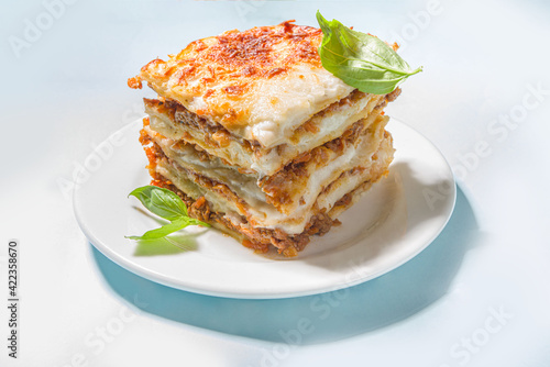 Mediterranean food, Italian traditional lasagna pasta, with bolognese, bechamel and cheese. On trendy breght light blue background with hard light and dark shadows copy space