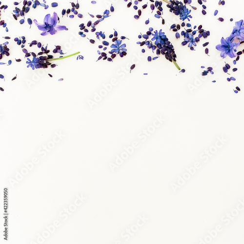 Frame with blue flowers and petals on white background. Flat lay