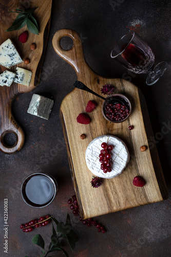 Different kinds of cheese on the wooden board with berries © pronina_marina