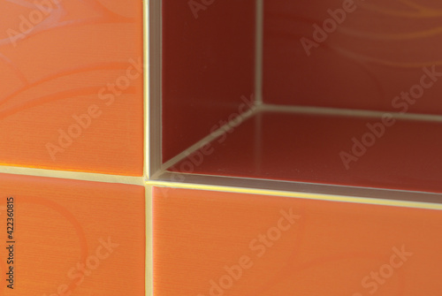 Close-up of a decorative element of the interior of the room - red-orange (terracotta) ceramic tiles on the wall. Photographia of the corner © Soap Dish