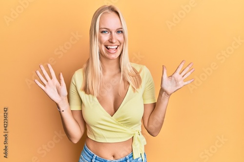 Young blonde girl wearing casual clothes showing and pointing up with fingers number ten while smiling confident and happy. © Krakenimages.com