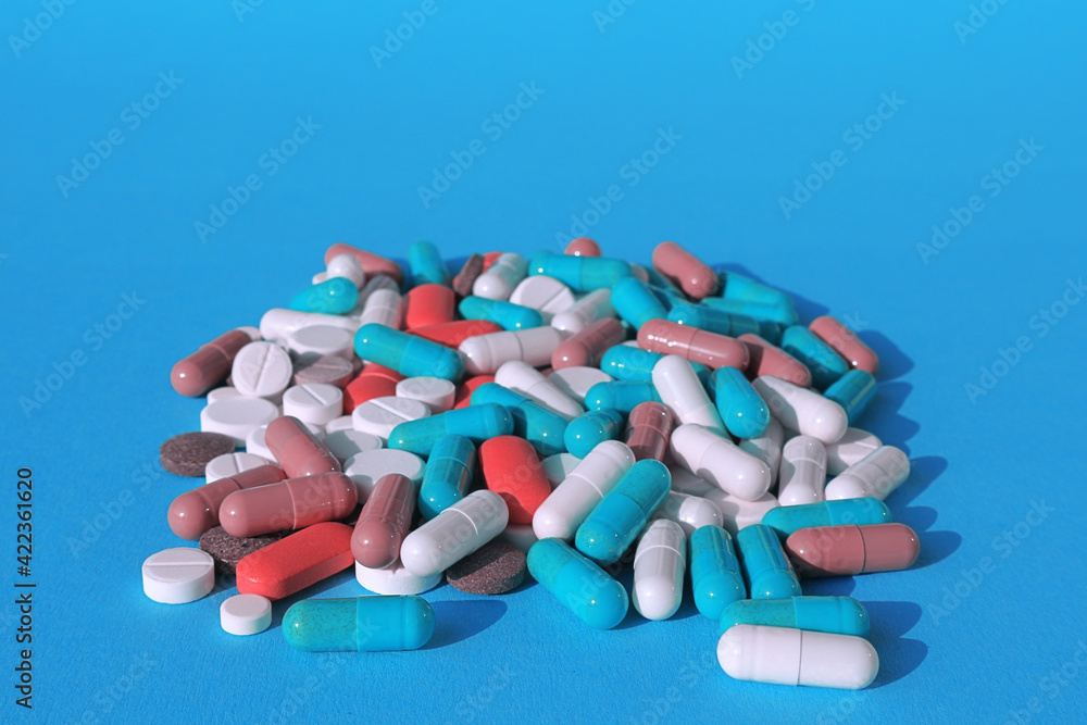 tablets, pills and capsules - medicines are poured on a blue background.