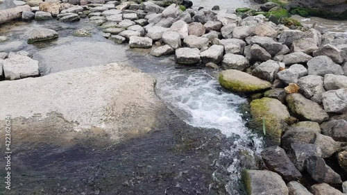 Clear stream of water cascades through the stones and flows into the sea. Nature concept.