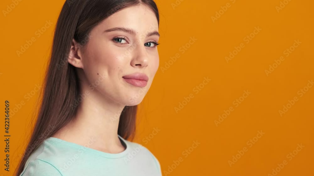A successful young woman is looking to the camera standing isolated over an orange background in the studio A successful young woman is looking to the camera standing isolated over an orange background in the studio