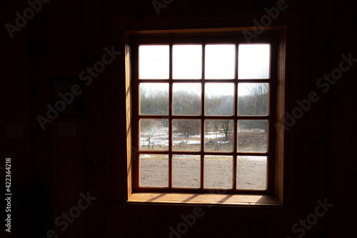 view from a dark room through a lattice window on the March forest