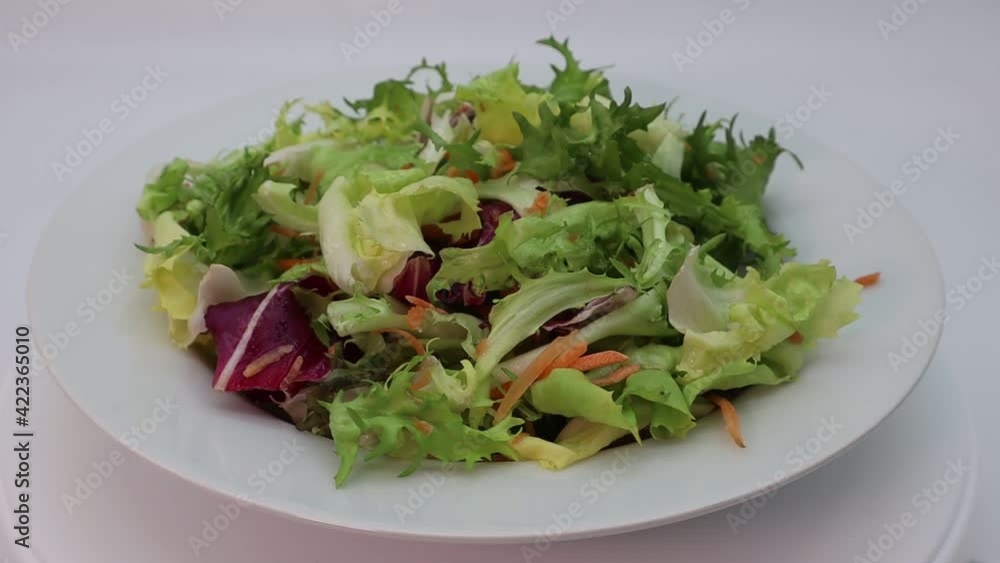 Fresh mixed green salad in a bowl rotating Fresh mixed green salad in a bowl rotating