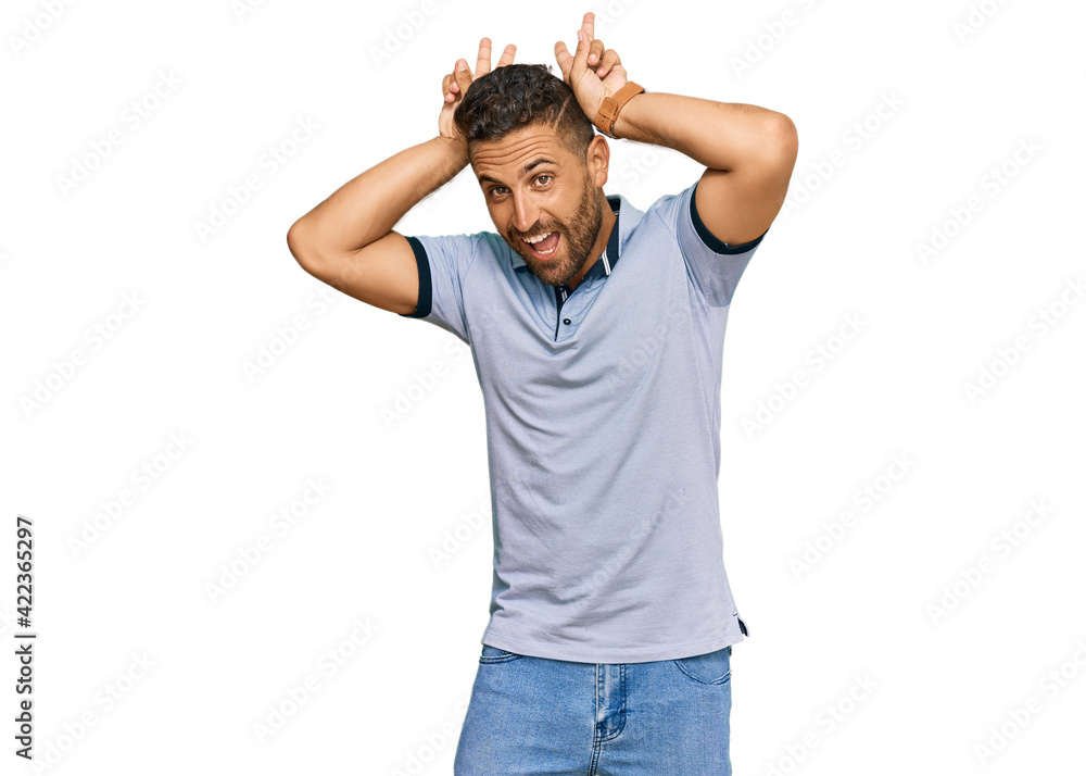 Handsome man with beard wearing casual clothes posing funny and crazy with fingers on head as bunny ears, smiling cheerful Handsome man with beard wearing casual clothes posing funny and crazy with fingers on head as bunny ears, smiling cheerful