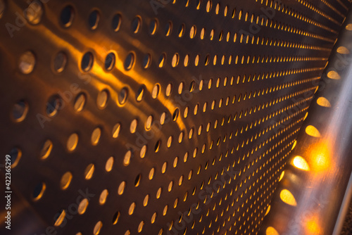 Εκτύπωση καμβά Closeup of abstract pattern background of stainless chrome metal sheet grille wall with circle holes with orange sun light pass through it