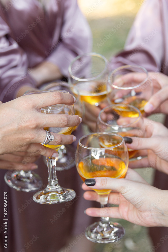 Champagne glasses in women's hands. Wedding morning bridal party. People clinking wine glasses.