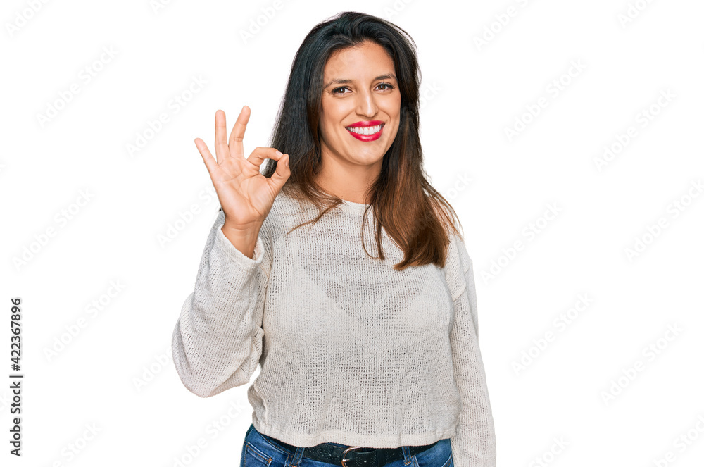 Beautiful hispanic woman wearing casual sweater smiling positive doing ok sign with hand and fingers. successful expression. Beautiful hispanic woman wearing casual sweater smiling positive doing ok sign with hand and fingers. successful expression.