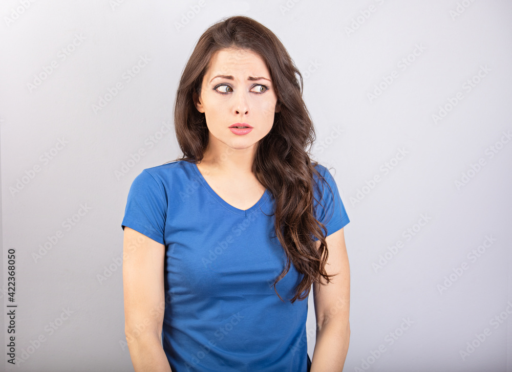 Pretty shocked woman with brunette hair and wide opened eyes in casual t-shirt dress looks scared. Studio shot Pretty shocked woman with brunette hair and wide opened eyes in casual t-shirt dress looks scared. Studio shot