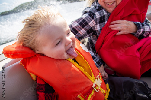 Happy baby wearing a life jacket, enjoying a motor boat ride at the cottage.