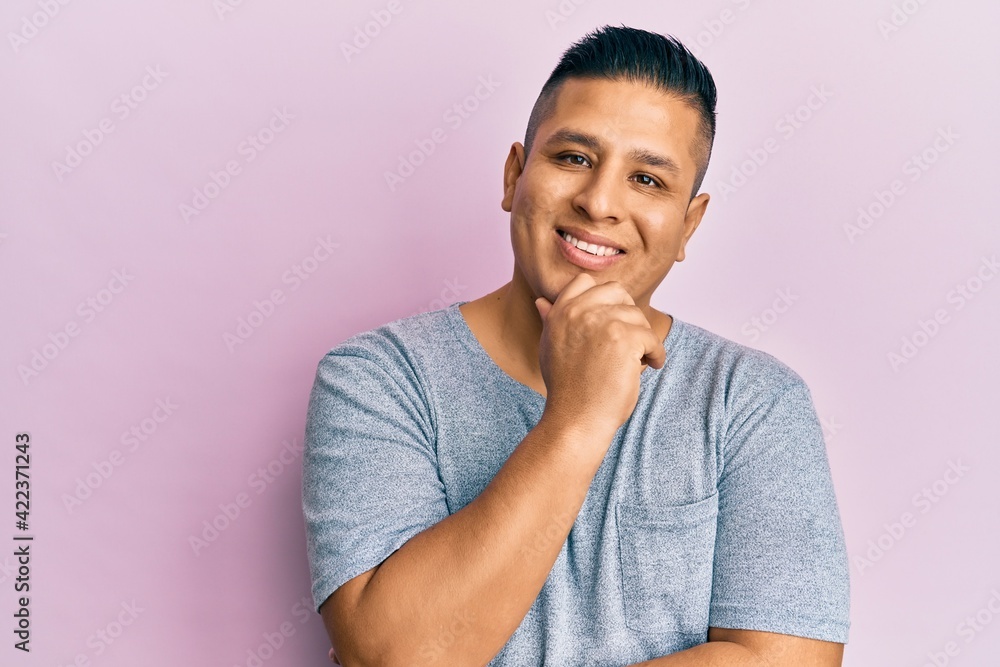 Young latin man wearing casual clothes smiling looking confident at the camera with crossed arms and hand on chin. thinking positive. Young latin man wearing casual clothes smiling looking confident at the camera with crossed arms and hand on chin. thinking positive.