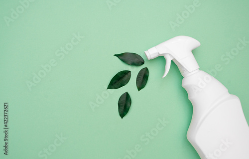 Eco spray for safe cleaning with fresh green leaves on a green background. Eco cleaning. House cleaning concept. Ecological object. Biological spring cleaning. view from above. copy space. Flat lay