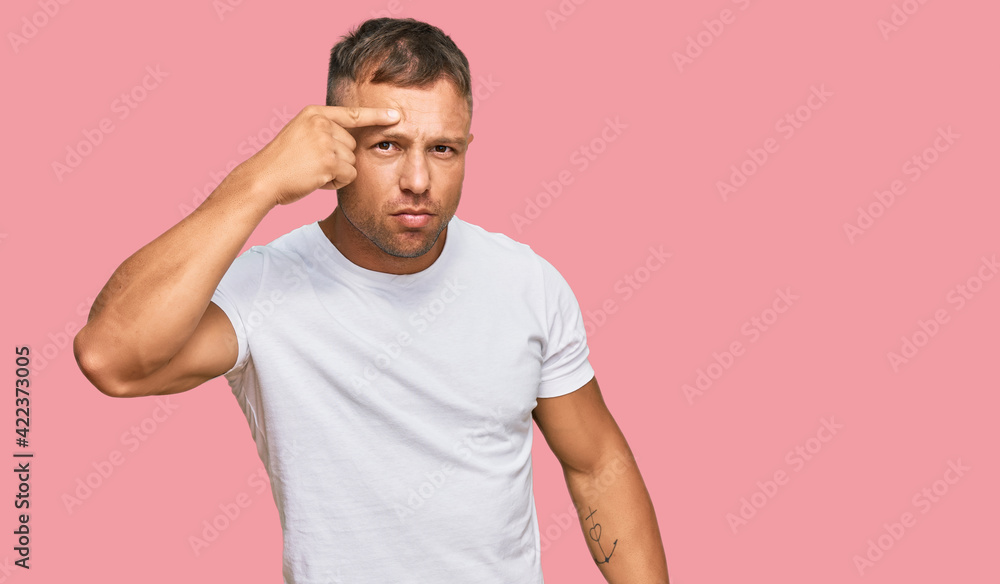 Handsome muscle man wearing casual white tshirt pointing unhappy to pimple on forehead, ugly infection of blackhead. acne and skin problem Handsome muscle man wearing casual white tshirt pointing unhappy to pimple on forehead, ugly infection of blackhead. acne and skin problem