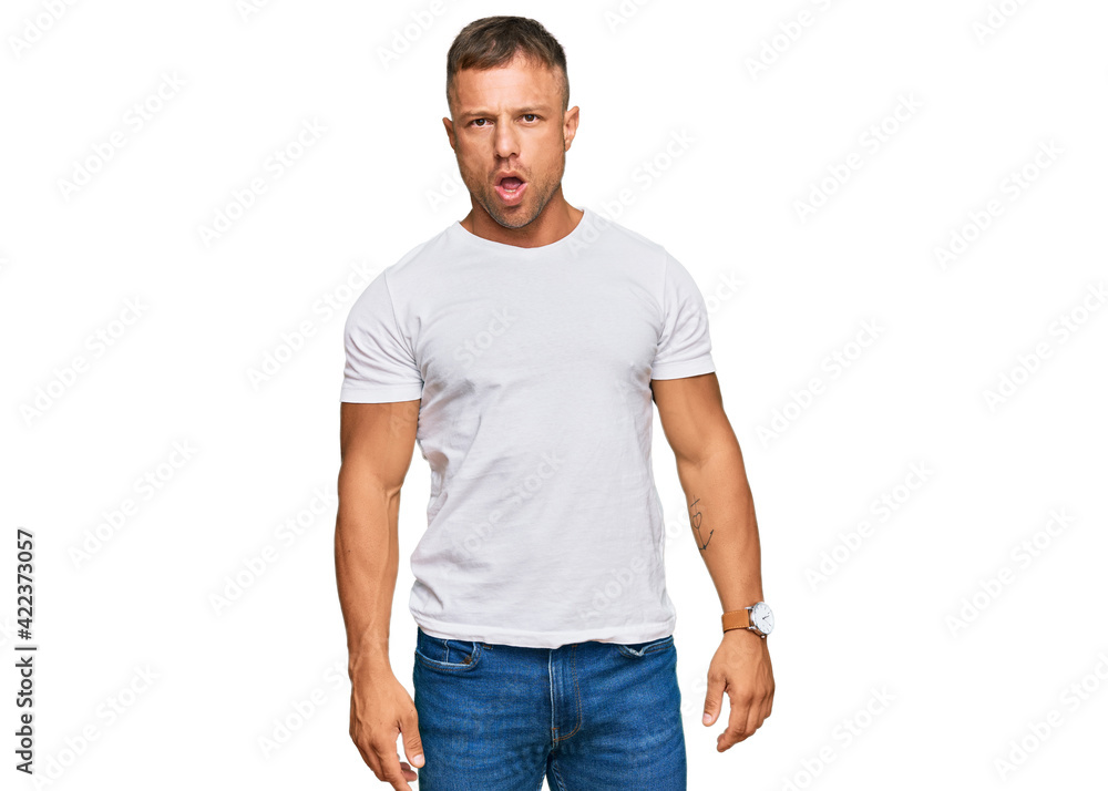 Handsome muscle man wearing casual white tshirt in shock face, looking skeptical and sarcastic, surprised with open mouth Handsome muscle man wearing casual white tshirt in shock face, looking skeptical and sarcastic, surprised with open mouth