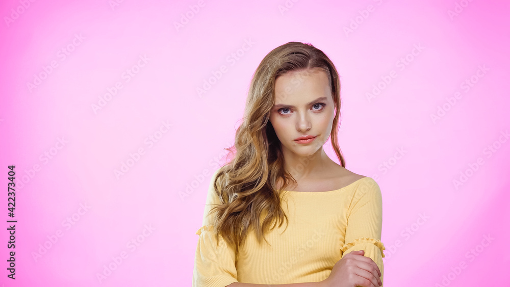 young woman with curly hair standing with crossed arms on pink young woman with curly hair standing with crossed arms on pink