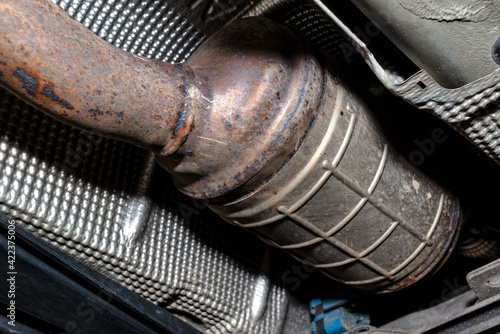 A diesel particulate filter in the exhaust system in a car on a lift in a car workshop, seen from below. photo