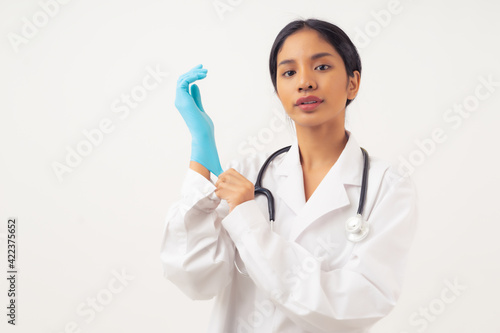Fotografie Portrait of young female doctor with stethoscope over neck, puts on protective g