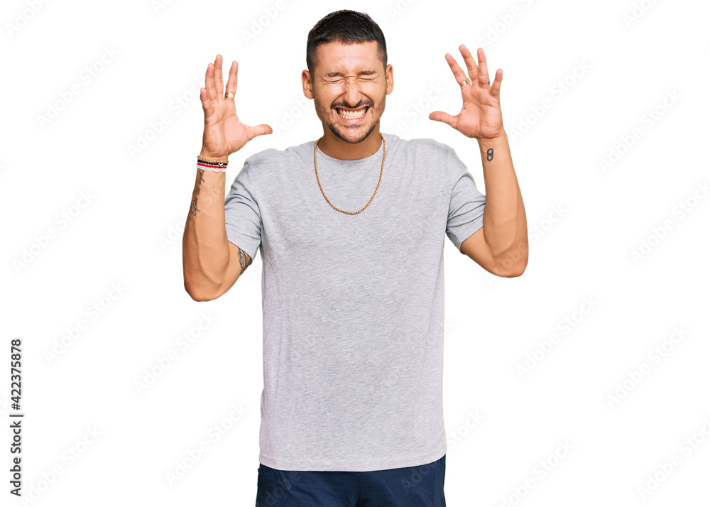 Fototapeta premium Handsome man with tattoos wearing 90s style celebrating mad and crazy for success with arms raised and closed eyes screaming excited. winner concept
