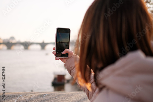 Blogger or influencer recording video from Prague. Vlogger shooting vlog on the mobile phone. Girl makes photo on her smartphone. Travel content