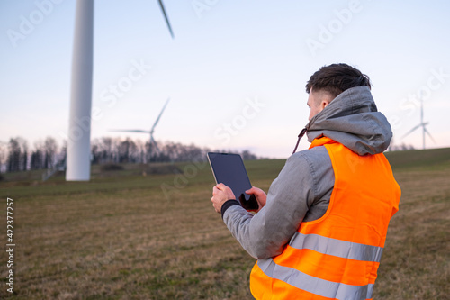 Electrical engineer checking or repairing wind turbines in the field using a tablet. 