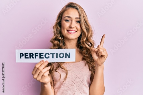 Billede på lærred Young blonde girl holding paper with perfection message smiling with an idea or
