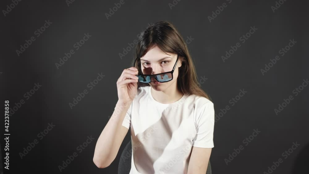 The woman slowly puts her sunglasses on her face. The woman slowly puts her sunglasses on her face.